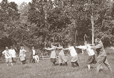 Photo of Charles Eastman (Ohiyesa) teaching archery at Camp Oahe